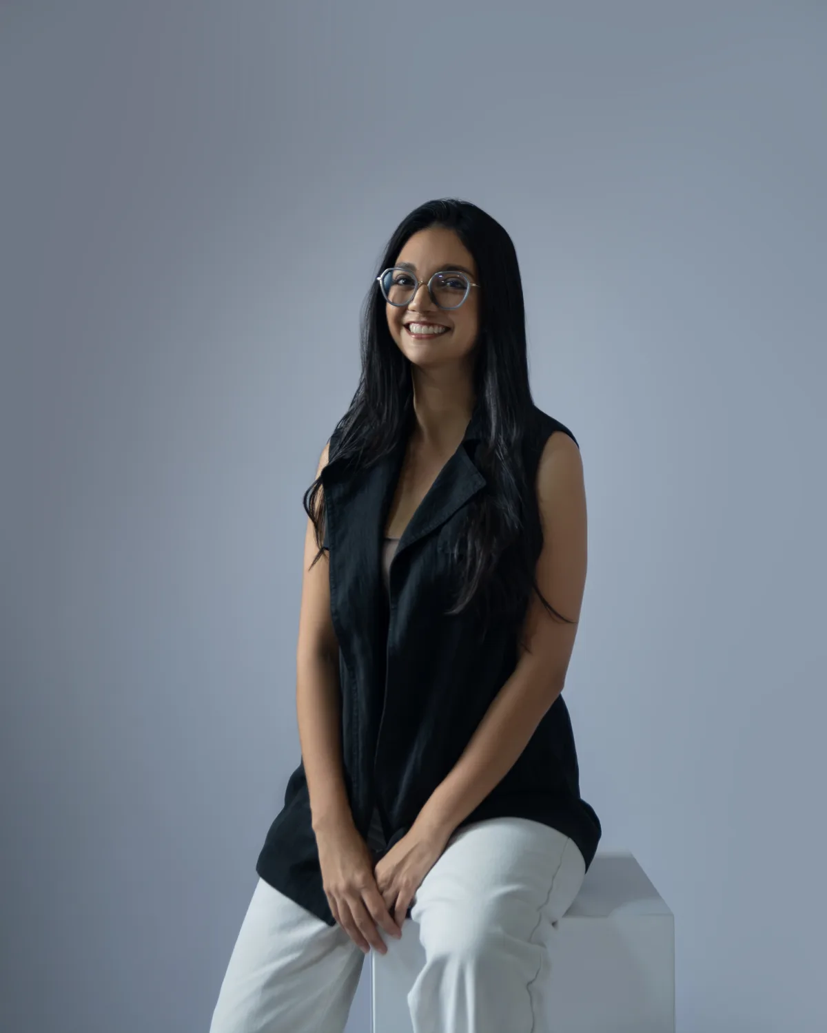 Elena Abarca, arquitecta de es.taller.arq, sonríe sentada sobre un bloque blanco.